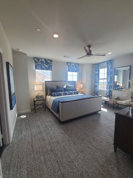 A cozy bedroom featuring blue and white decor, plush carpet, and ample natural light from large windows. A cozy bedroom featuring blue and white decor, plush carpet, and ample natural light from large windows.