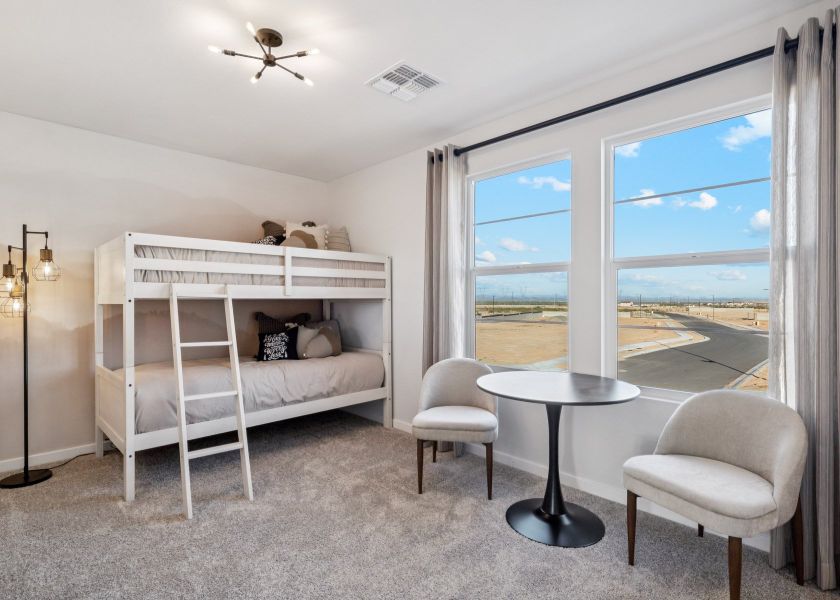 A room with a bed and chairs.