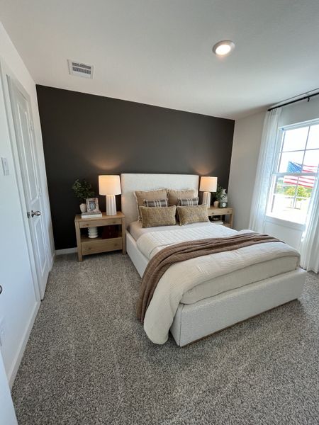 Cozy bedroom featuring a soft carpet, modern bed, warm-toned linens, and elegant side tables with soft lighting.