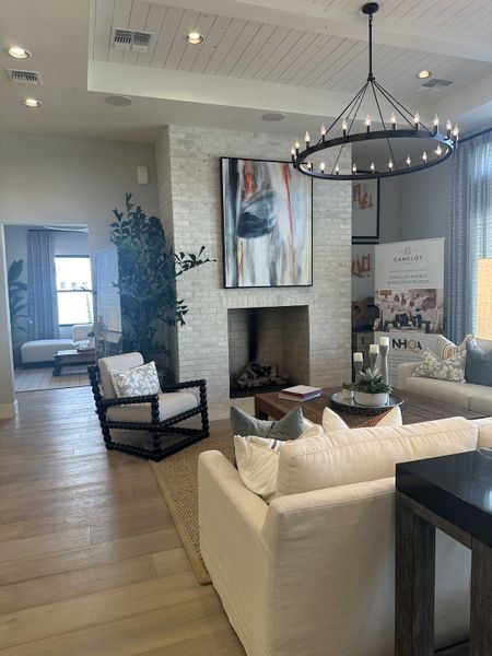 Elegant living room with cozy seating, modern art, and a striking chandelier creating a warm and inviting atmosphere.