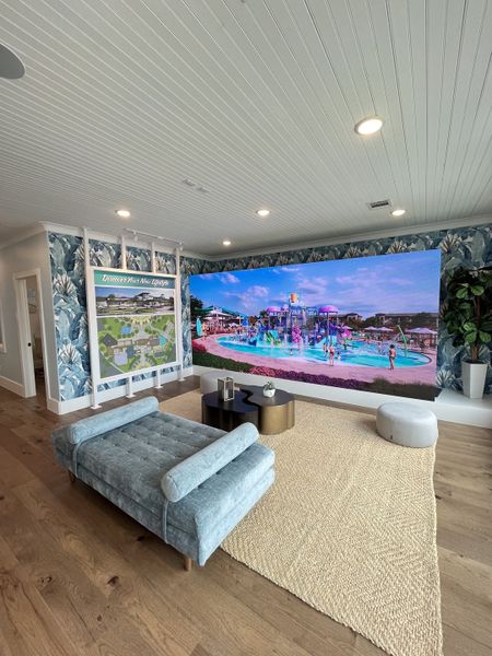 A cozy room with a plush chaise, textured wallpaper, and a large display screen showcasing a vibrant outdoor scene.