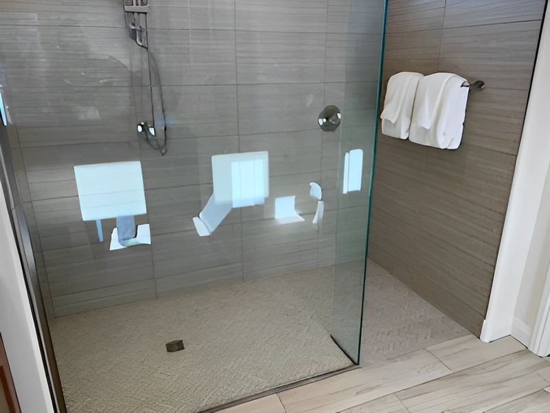 A sleek shower with modern glass doors, tiled walls, and a subtle stone floor for a luxurious bathing experience.