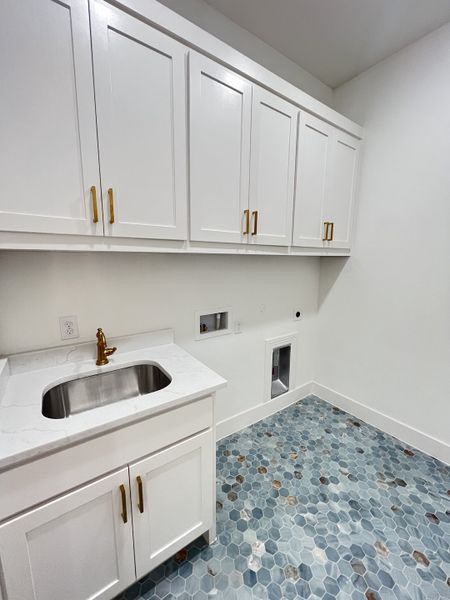 A stylish laundry room with white cabinetry, brass hardware, and blue hex tile flooring. A stylish laundry room with white cabinetry, brass hardware, and blue hex tile flooring.
