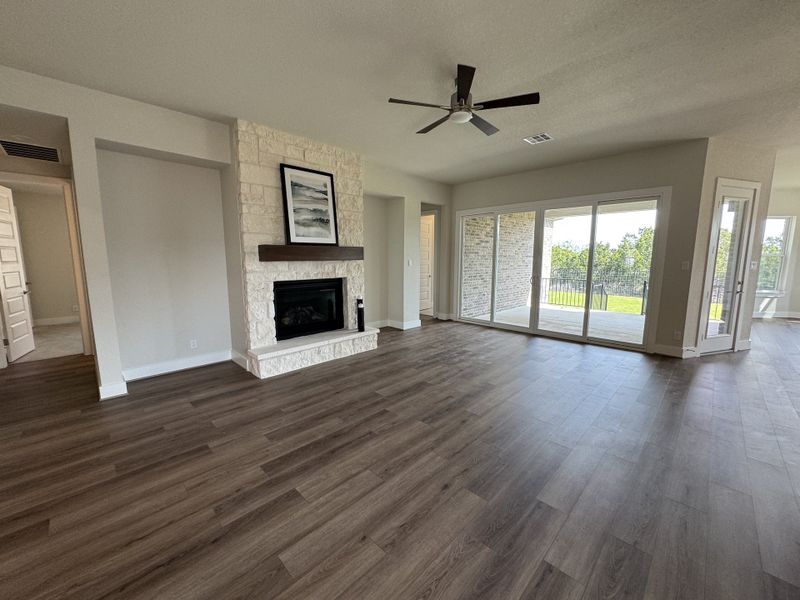 An elegant living room with a stone fireplace, wood floors, and large glass doors opening to a scenic view.