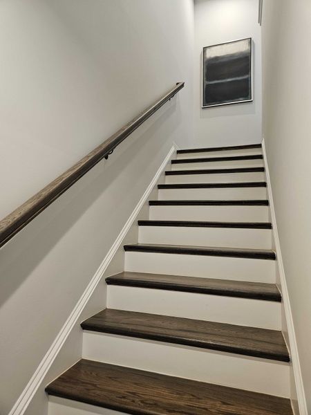 A sleek staircase with wooden steps and metal railing, highlighted by a modern abstract painting at the landing. A sleek staircase with wooden steps and metal railing, highlighted by a modern abstract painting at the landing.