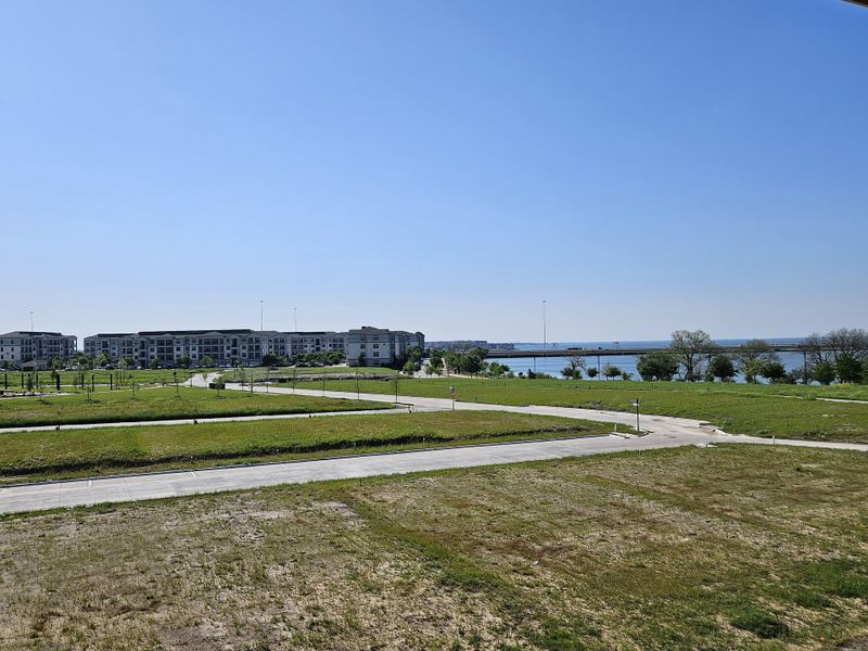 A scenic view of greenery and water in the Bayside community by Beazer Homes in Rowlett, TX, with modern apartments nearby.