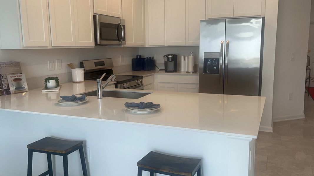 A modern kitchen with sleek white cabinets, stainless steel appliances, and a spacious island with seating.