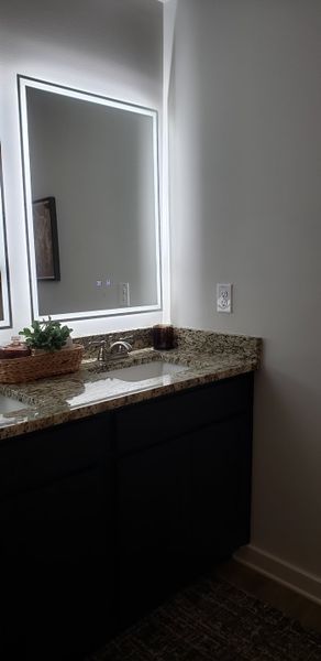 A sleek bathroom with a granite countertop, LED-lit mirror, and modern fixtures creating a luxurious feel. A sleek bathroom with a granite countertop, LED-lit mirror, and modern fixtures creating a luxurious feel.