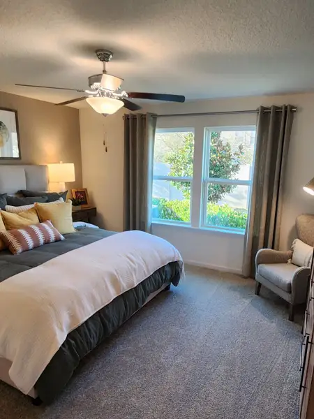 A cozy bedroom with a fan and creative décor in Panther Creek by KB Home (Jacksonville, FL).