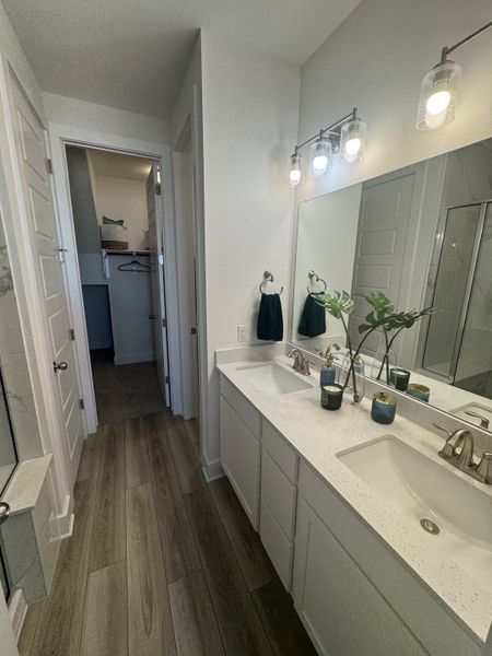 A modern bathroom with double sinks, sleek lighting, and wood-look flooring for a stylish and functional space.