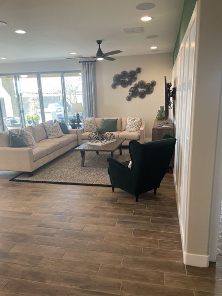 A cozy living room with a spacious sectional, modern decor, wood-look tile flooring, and large windows for natural light. A cozy living room with a spacious sectional, modern decor, wood-look tile flooring, and large windows for natural light.