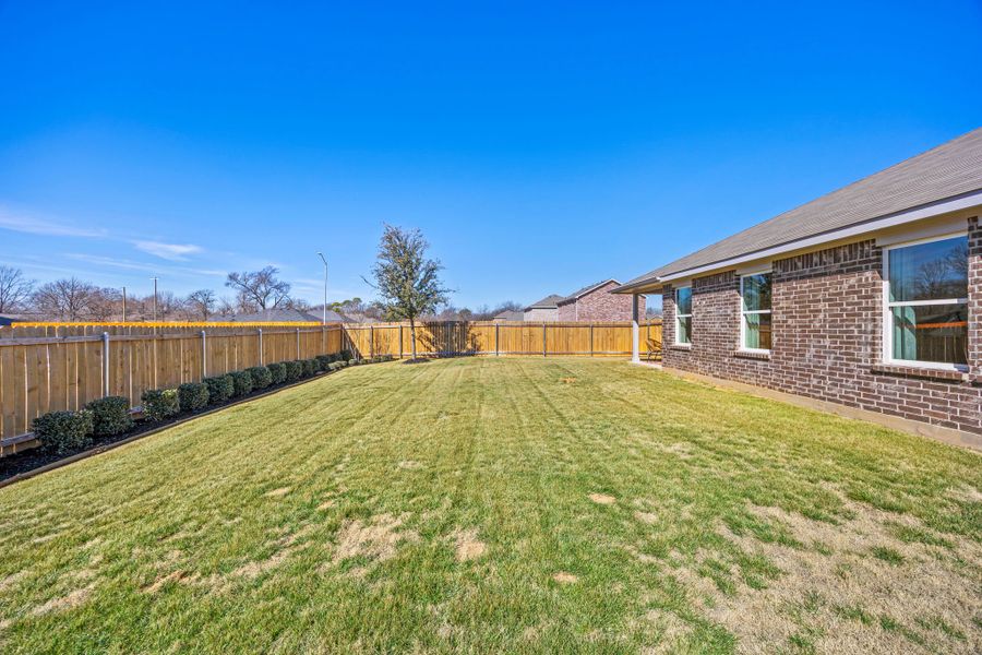 A fenced in yard with a house and trees in the background. A fenced in yard with a house and trees in the background.