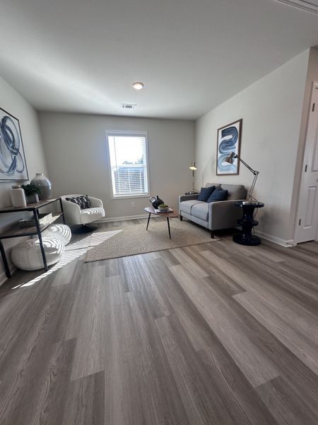 A bright living area with wood floors, cozy seating, modern decor, and a central window for ample natural light. A bright living area with wood floors, cozy seating, modern decor, and a central window for ample natural light.