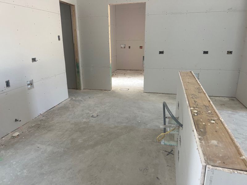 A spacious room in progress featuring drywall and a concrete floor, ready for finishing touches. A spacious room in progress featuring drywall and a concrete floor, ready for finishing touches.