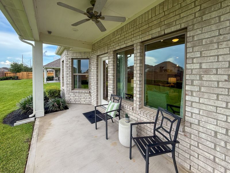 A cozy patio with black chairs and views of a lush green lawn.