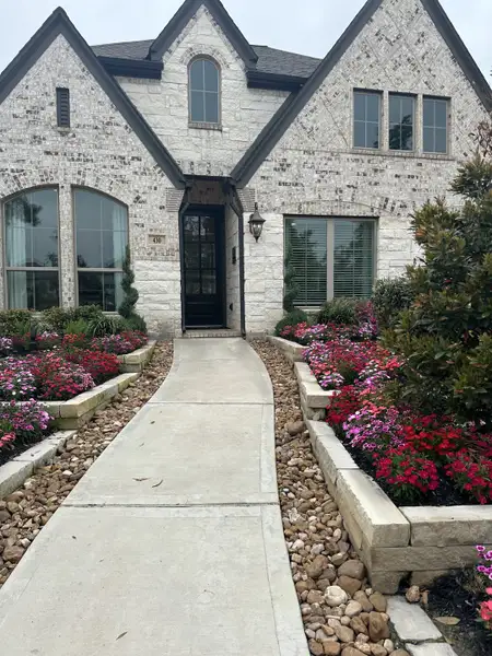 A charming stone home with lush flower beds in Grand Central Park 50' by Perry Homes (Conroe, TX).