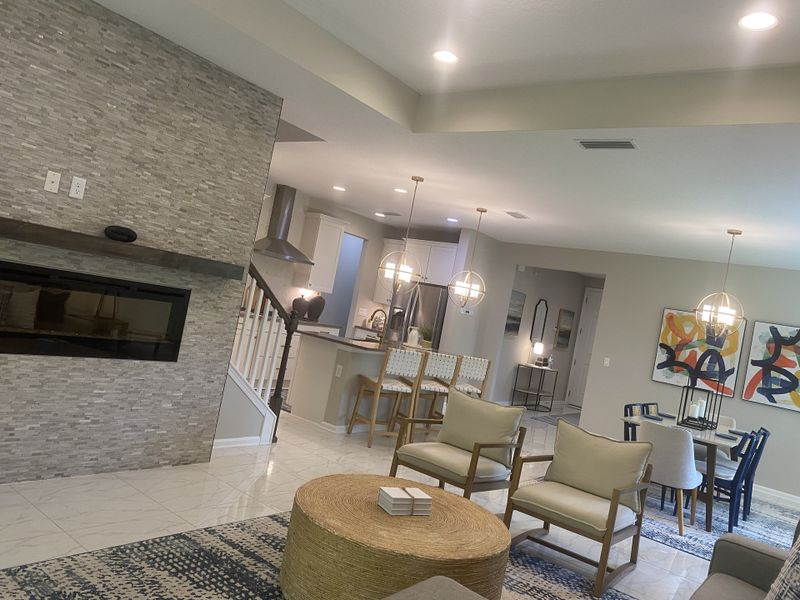 A modern open-concept living area with a sleek stone fireplace, elegant lighting, and stylish dining space. A modern open-concept living area with a sleek stone fireplace, elegant lighting, and stylish dining space.