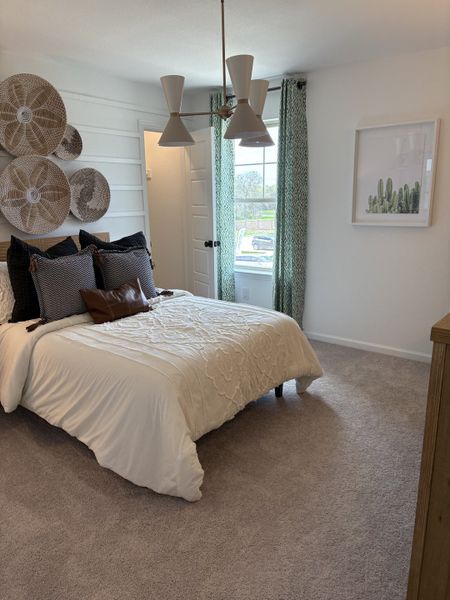 A cozy bedroom featuring woven wall art, elegant lighting, and soft neutral tones for a serene atmosphere.