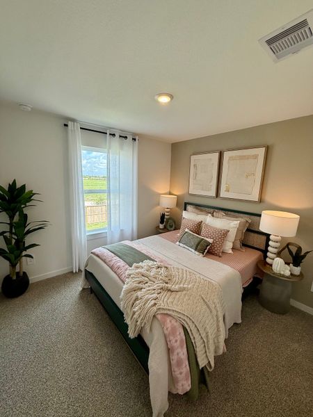 A cozy bedroom featuring a plush bed, stylish decor, soft lighting, and a large window with sheer curtains.