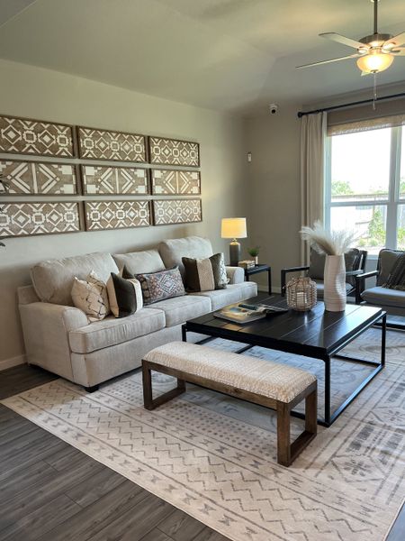 A cozy living room with a plush sofa, patterned artwork, and a sleek black coffee table on a soft, geometric rug.