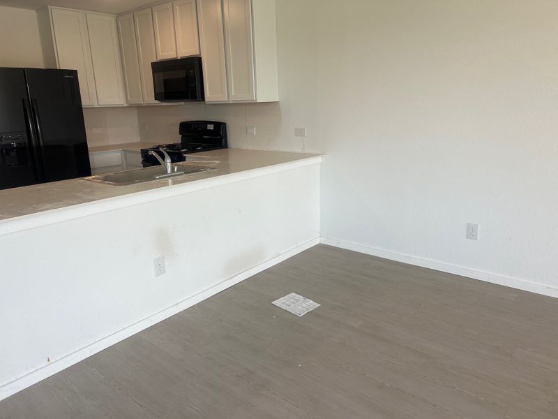 A sleek kitchen featuring white cabinetry, a black fridge, modern appliances, and a spacious counter for dining and prep. A sleek kitchen featuring white cabinetry, a black fridge, modern appliances, and a spacious counter for dining and prep.