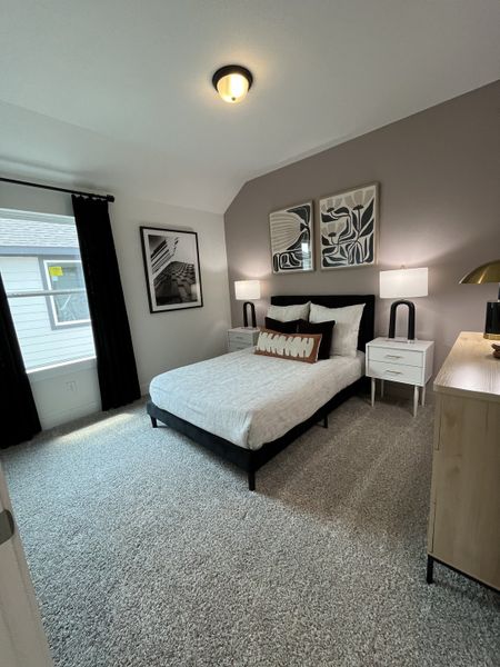 A cozy bedroom featuring modern artwork, a chic bed, and plush carpeting for a comfortable retreat.