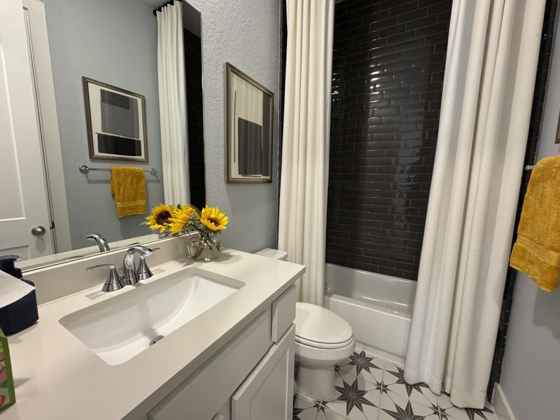 A modern bathroom with black tile, floral accents, and a sleek vanity paired with stylish decor. A modern bathroom with black tile, floral accents, and a sleek vanity paired with stylish decor.