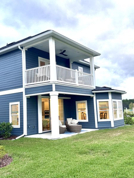 A beautiful blue two-story home with a cozy patio in Brook Forest by Dream Finders Homes (St. Augustine, FL).