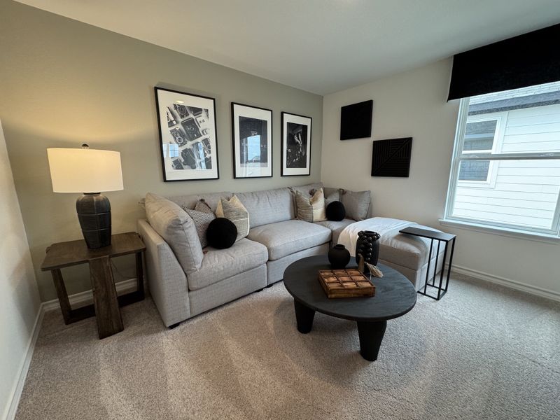 A cozy living area featuring a plush gray sectional, modern art, and stylish black accents. Perfect for relaxation and entertaining.