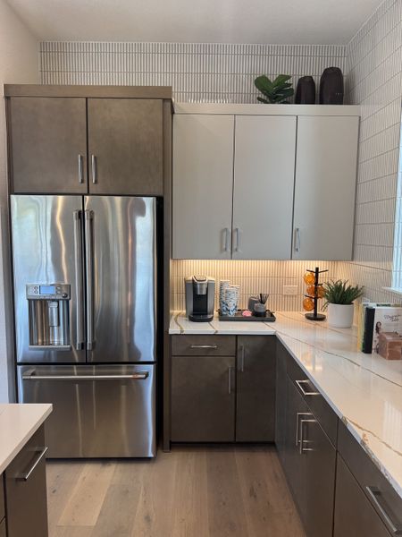 A modern kitchen with sleek cabinetry, stainless appliances, and light wood flooring.