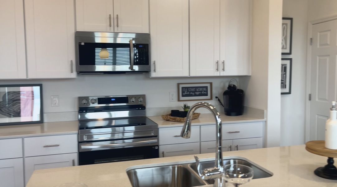 A modern kitchen featuring sleek stainless steel appliances, white cabinetry, and a chic faucet with double sink.