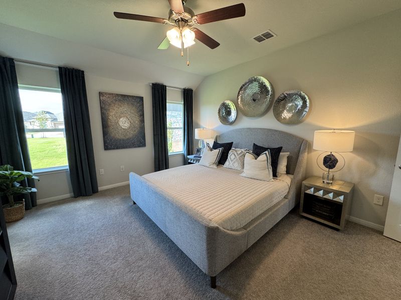 A cozy bedroom featuring a plush bed, elegant decor, ceiling fan, and ample natural light from dual windows. A cozy bedroom featuring a plush bed, elegant decor, ceiling fan, and ample natural light from dual windows.