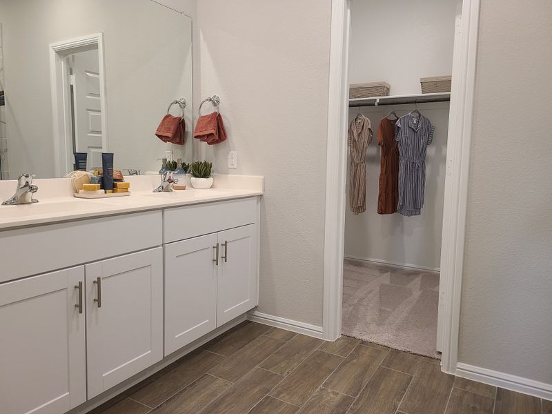 Modern bathroom with double vanity, sleek fixtures, and an inviting walk-in closet for streamlined organization.