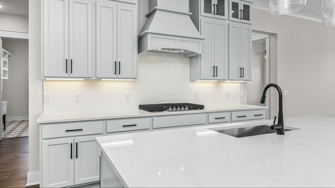 Up-close image of kitchen with light cabinetry, tile backsplash, and quartz countertops Up-close image of kitchen with light cabinetry, tile backsplash, and quartz countertops