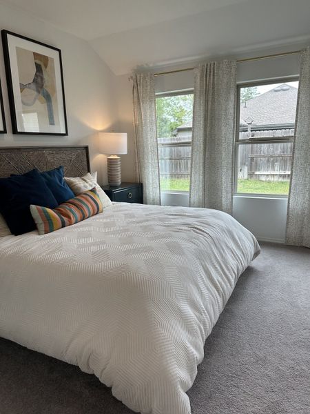 A cozy bedroom with a textured white comforter, large windows, and abstract wall art, offering a serene retreat. A cozy bedroom with a textured white comforter, large windows, and abstract wall art, offering a serene retreat.