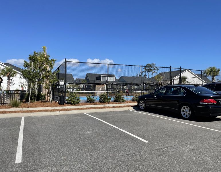 A vibrant tennis court with lush greenery in Encore - Restore at Carolina Park - Classic Series by David Weekley Homes (Mount Pleasant, SC).
