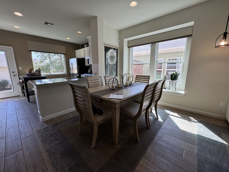 A bright kitchen and dining area with sleek cabinetry, a large island, and ample natural light through expansive windows. A bright kitchen and dining area with sleek cabinetry, a large island, and ample natural light through expansive windows.