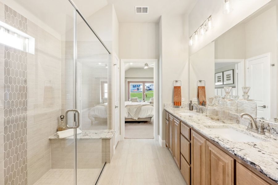Ensuite bathroom with double vanity, granite countertops, and glass walk-in shower with tile bench seat