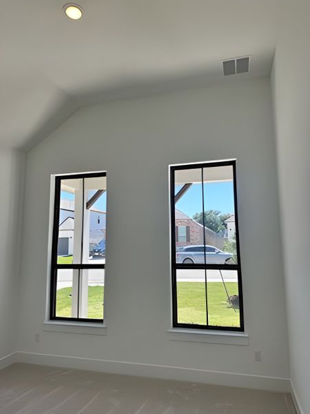 Bright room with high ceilings, large modern windows, and a serene view of the grassy exterior.