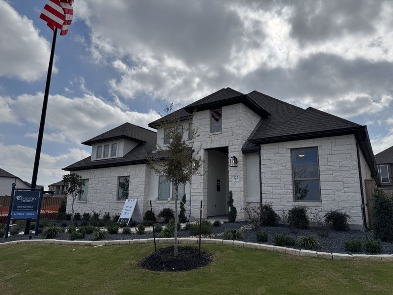 A beautiful white stone home with landscaped yard in Mayfair 50' Homesites by Coventry Homes, New Braunfels, TX.