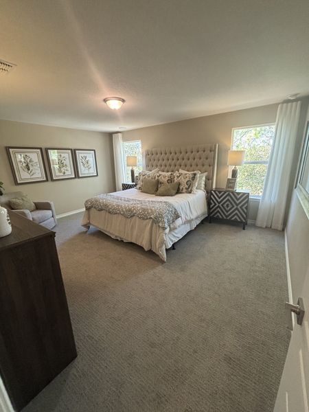 A cozy bedroom featuring a tufted headboard, patterned bedding, and elegant decor with soft lighting. A cozy bedroom featuring a tufted headboard, patterned bedding, and elegant decor with soft lighting.