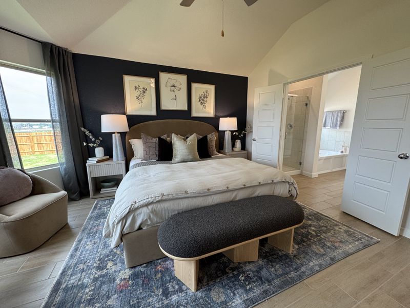 A cozy bedroom with elegant decor, featuring a plush bed, stylish artwork, and access to an en-suite bathroom.
