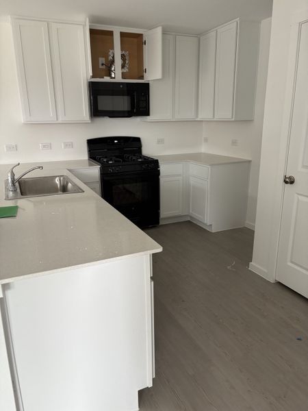 A sleek kitchen with white cabinets, quartz countertops, and modern appliances.