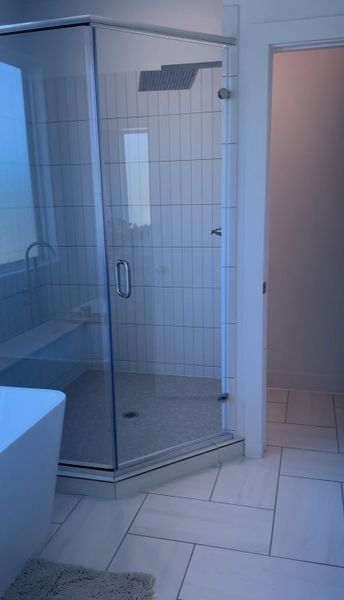 A sleek bathroom featuring a glass-enclosed shower, elegant white tile, and modern fixtures.