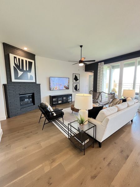 A modern living room with a black accented fireplace, sleek furnishings, and large windows for natural light. A modern living room with a black accented fireplace, sleek furnishings, and large windows for natural light.