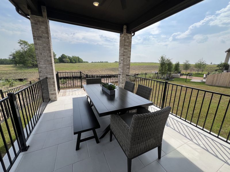 A cozy patio with stylish seating, overlooking an open field, perfect for outdoor dining and relaxation.