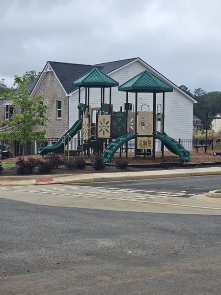 A vibrant playground nestled in Fern Dale by Dream Finders Homes, Fairburn, GA, with charming homes and lush greenery.