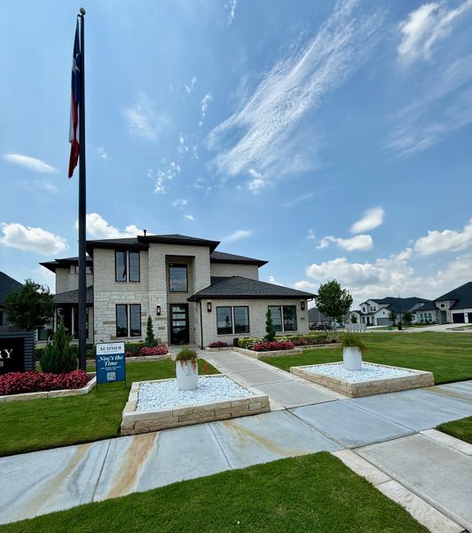A modern stone home with lush landscaping in Stonecreek Estates 60' by Perry Homes (Richmond, TX).