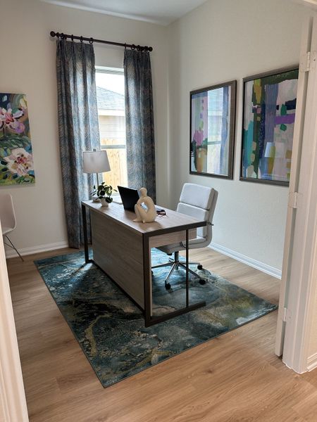 A cozy home office with a wooden desk, abstract artwork, and elegant drapery, creating a serene workspace.