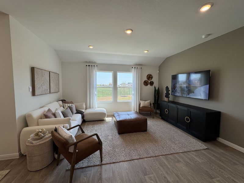A cozy living room featuring a plush sofa, elegant decor, and a large TV, bathed in natural light from a picturesque window. A cozy living room featuring a plush sofa, elegant decor, and a large TV, bathed in natural light from a picturesque window.